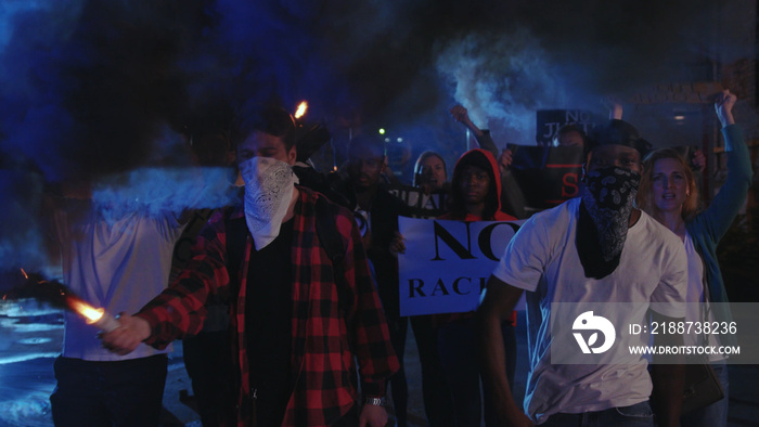 Aggressive black leader walking in front of riot crowd, shouting slogans at policemen, fighting against violence and injustice. Black lives matter. No racism concept.