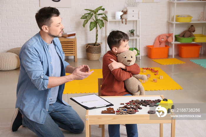 Male psychologist working with little boy in office. Autism concept