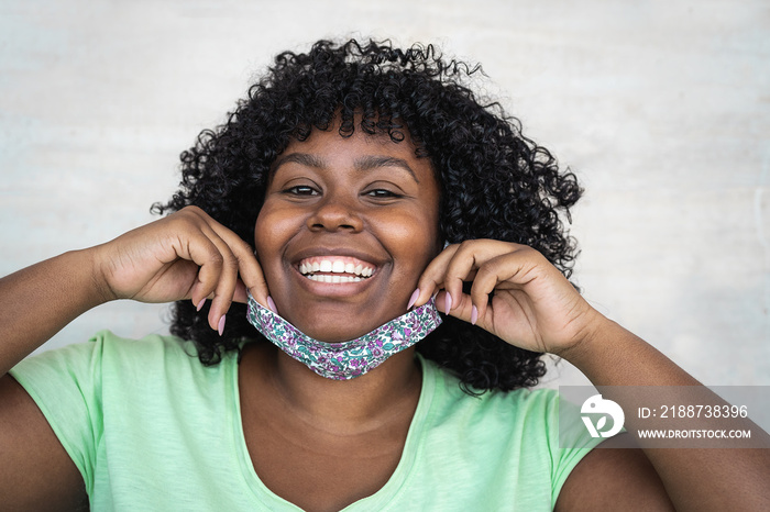 Happy Afro woman portrait - African girl wearing face mask smiling in front of camera - Health care and corona virus outbreak concept