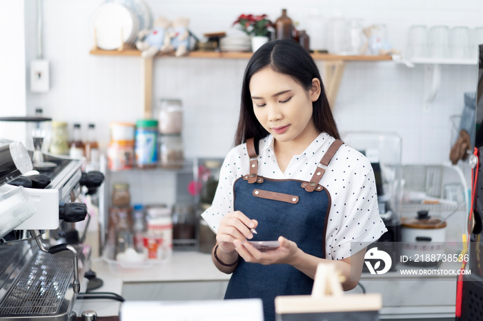 Asian women waiter hands on notebook, taking customer orders in restaurant or cafeteria, Thai girl coffee shop worker wearing apron write order serving for a client, writing food list service concept