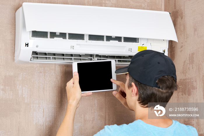 male technician service worker diagnosing for repairs air conditioner. person using tablet. diy concept