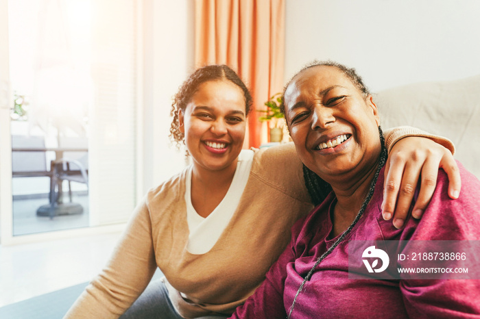 Mother and daughter doing fitness exercises at home together - Family and sport concept during winter time - Focus on senior woman face