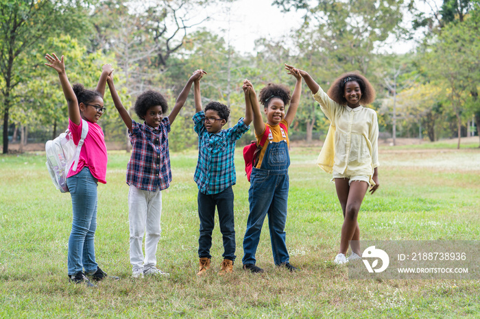 Happy fun group of African American children raised hands together in the park, Education outdoor concept