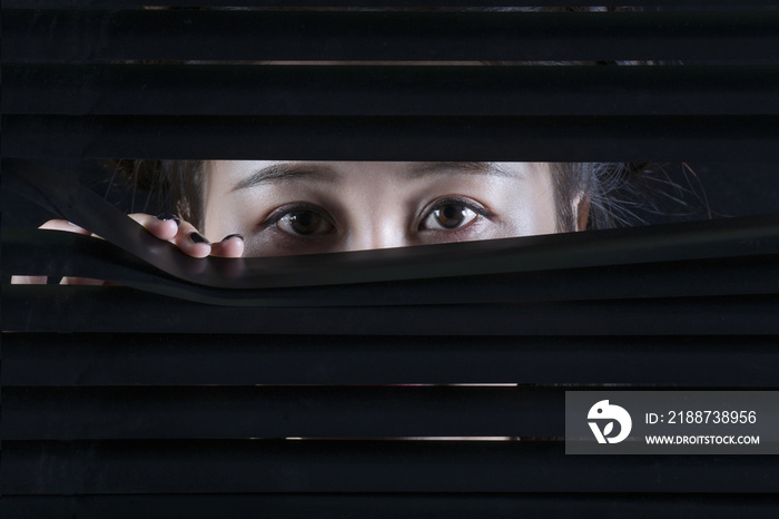 Oriental woman looking through a blind