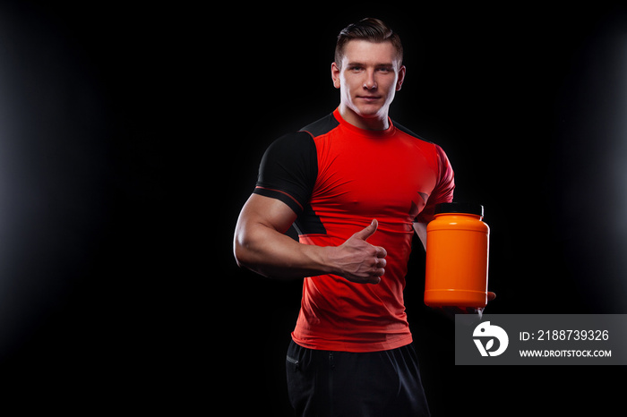 Happy and healthy muscular young fitness sports man with a jar of sports nutrition - protein, gainer and casein.