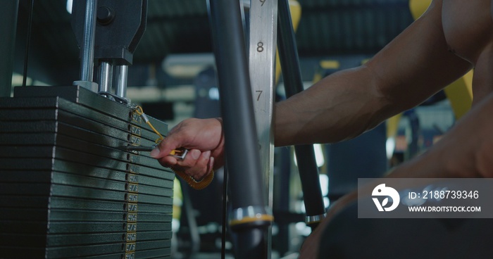 Closeup hands of athlete man chooses weight in the sports equipment in exercise machine, muscle sportsman choosing different weightlifting options for lifting training workout at fitness gym