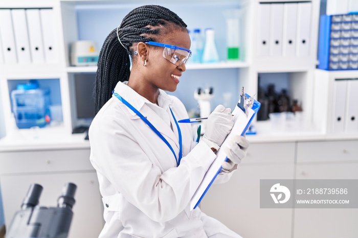 African american woman scientist writing report working at laboratory