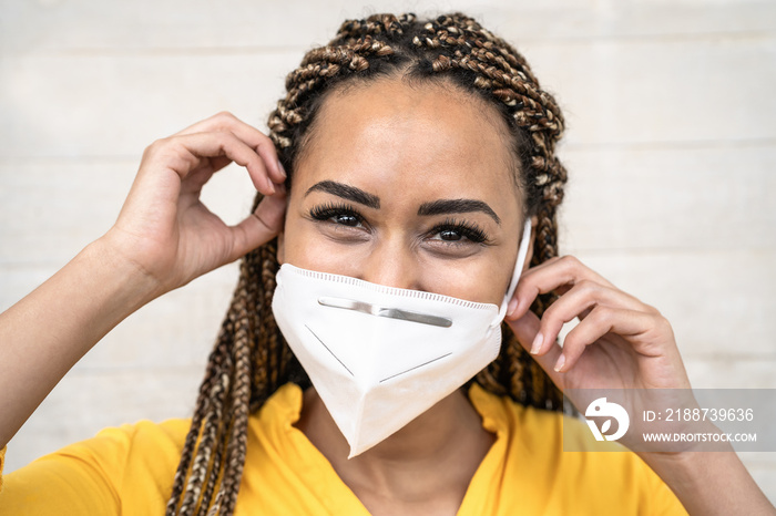 Young Afro woman with braids wearing face medical mask portrait - African girl using facemask for preventing and stop corona virus spread - Healthcare medical and youth millennial people concept