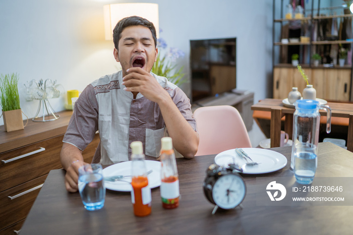 tired muslim male wake up early to have a morning breakfast on fasting month. sahur concept in ramadan