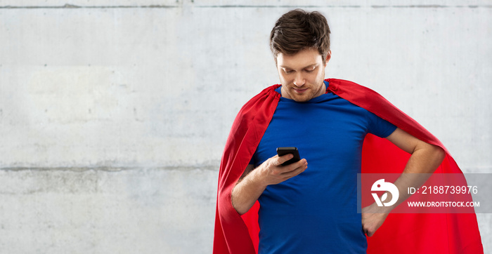 super power, technology and people concept - young man in red superhero cape using smartphone over grey concrete background