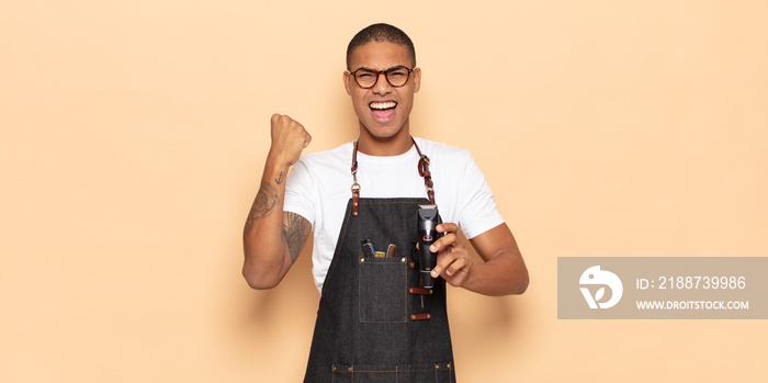 young black man shouting aggressively with an angry expression or with fists clenched celebrating success