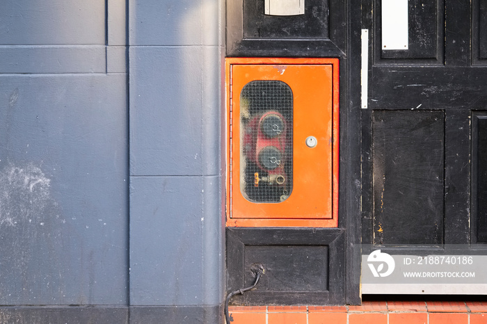 Dry riser inlet box red on brick wall for emergency fire services water connection for hose brigade engine at house entrance door