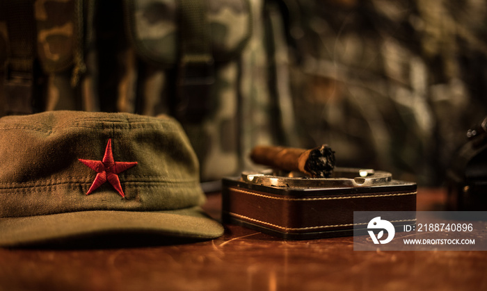 Close up of a Cuban cigar and ashtray on the wooden table. Communist dictator commander table in dark room. Army general`s work table concept.