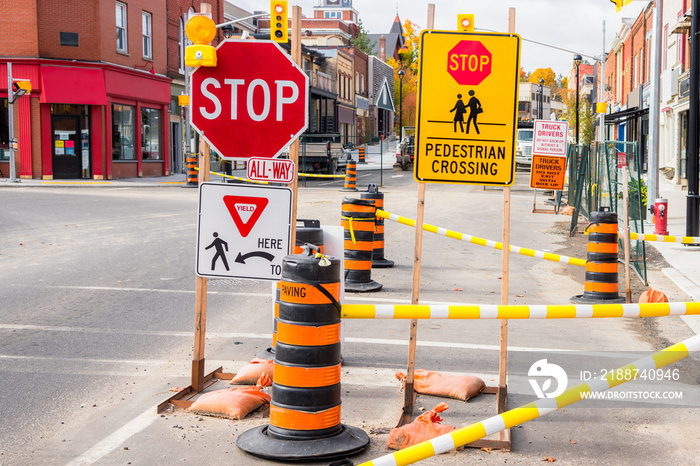 Traffic cones and warning signs indicating the closure of a street because of roadworks in a historic downtown district on a sunny autumn morning