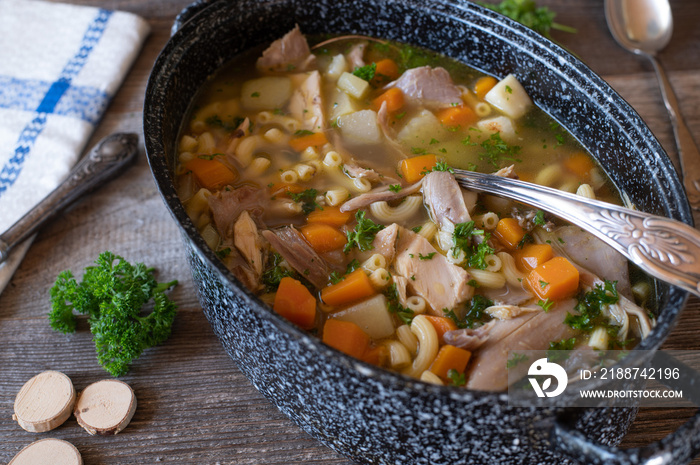 fortifying chicken soup or stew in a rustic pot. Fresh and homemade cooked.