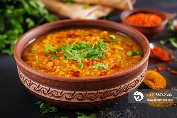 Indian dal. Traditional Indian soup lentils.  Indian Dhal spicy curry in bowl, spices, herbs, rustic black wooden background. Authentic Indian dish. Overhead