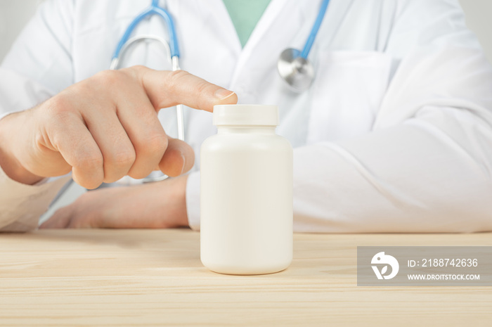 doctor holding white bottle of tablets or pills with a blank white label for treatment of an illness or injury. Doctor’s appointment blank pills bottle.