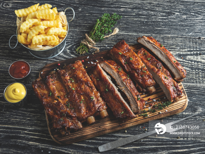 grilled pork ribs with sauce on a cutting board, french fries