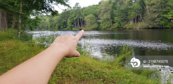 right Human hand pointing with a finger in nature next to a river