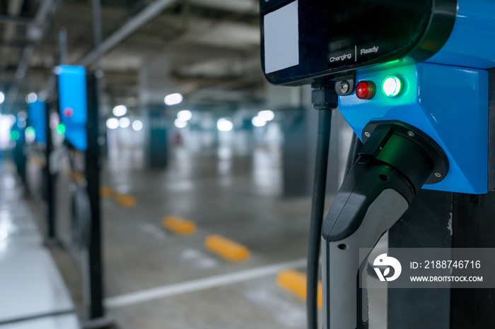 Electric car charging station for charge EV battery. Plug for vehicle with electric engine. EV charger. Clean energy. Charging point at car parking lot. Green power. Future transport technology.