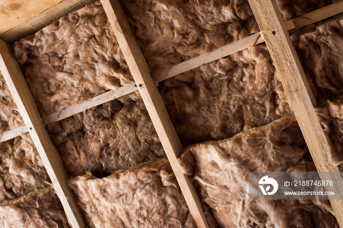 Glass wool in a wooden frame on a inclined wall near the wooden ceiling in a private house. Warming the house with fiberglass.