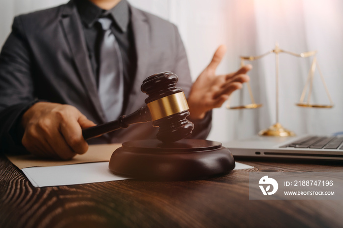 Justice and law concept.Male judge in a courtroom with the gavel, working with, computer and docking keyboard, eyeglasses, on table in morning light