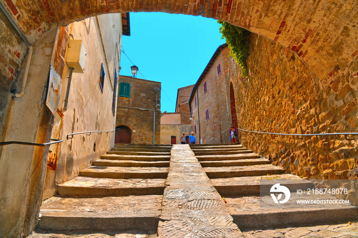 The narrow stone street with steps and arch in the historical center of Castiglione della Pescaia, Grosseto Tuscany, Italy