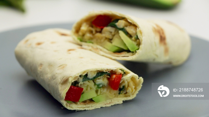 Healthy lunch snack. Tortilla wraps with Avocado, Spinach, Cheese and Bell Pepper on a Grey Plate on a White Background