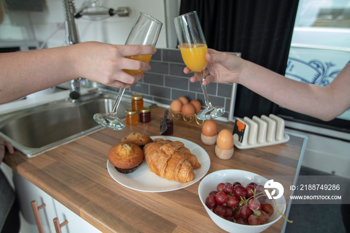 A celebration breakfast is served in this trendy renovated camper van, includes eggs, croissants, orange juice etc served on wooden kitchen surface and grey tiled kitchen area