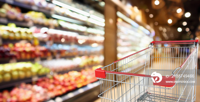 supermarket grocery store with fruit and vegetable shelves interior defocused background with empty red shopping cart