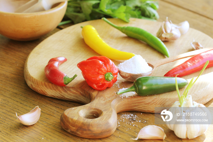 different variety of hot peppers and spices on cutting board