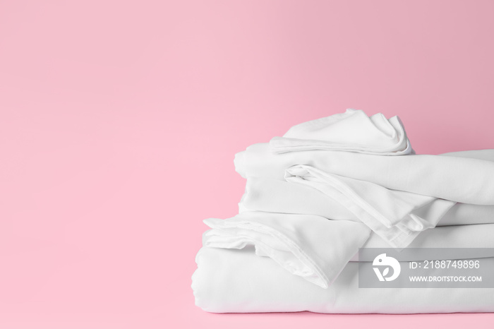 Stack of clean bed sheets on color background