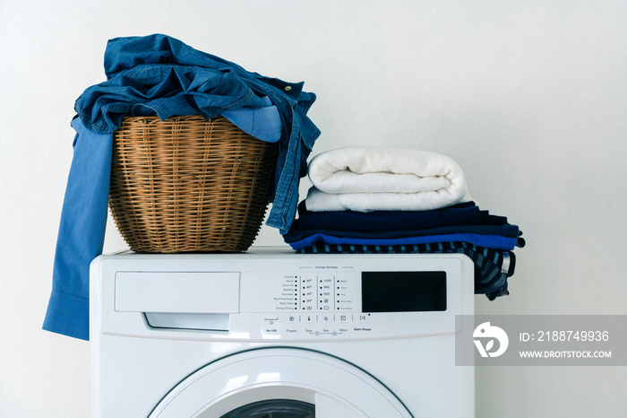 Close up clothes in basket and pile fabric on washing machine with white background. Laundry concept.