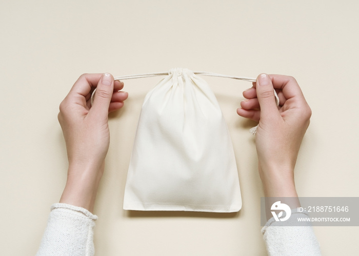 woman closing a small cotton storage pouch. eco-friendly white cotton bag with ties