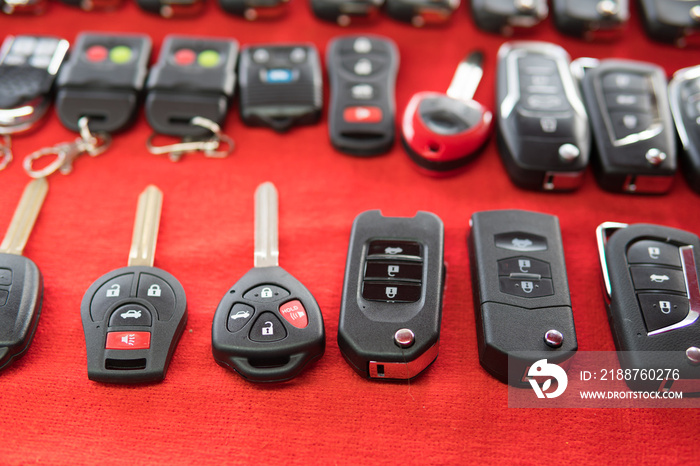 Locksmith stand with variety of car and van keys remote on red background