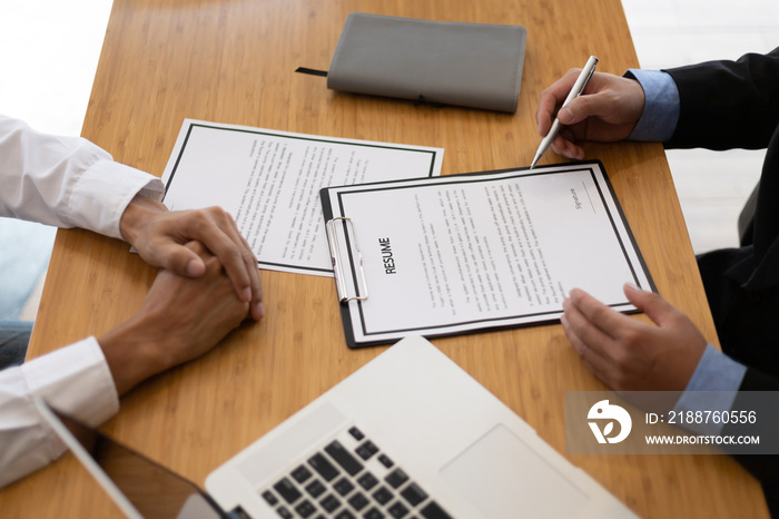 The manager holding the papers is reading the resume and interviewing the applicant or new employee in the employment office.