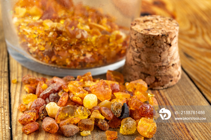 Small raw amber in a glass bottle on a wooden table. A precious find from the coast of Central Europe.