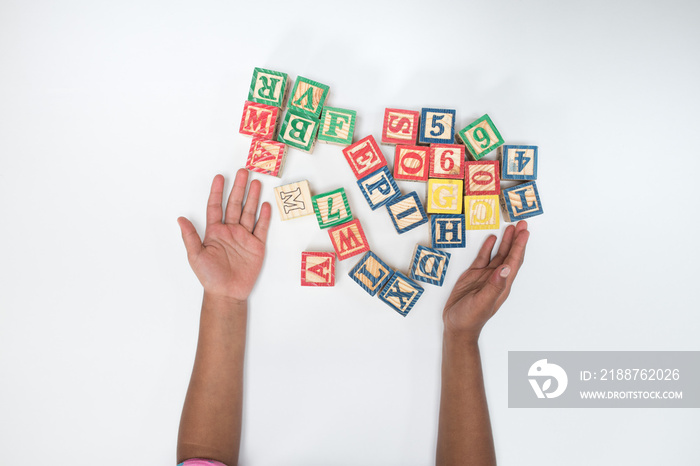 Symbolbild für Schule und Bildung - Textfreiraum -   Kinderhände mit Buchstaben auf weißem Hintergrund