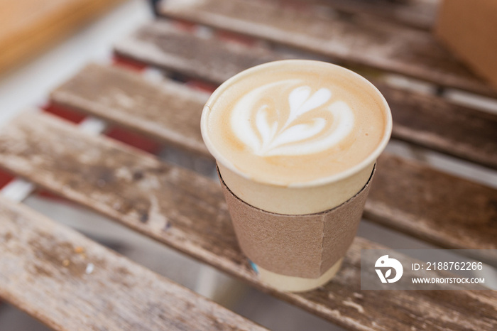 Soft focus of Latte art hot coffee in eco paper cup on table background. Street coffee, top view.