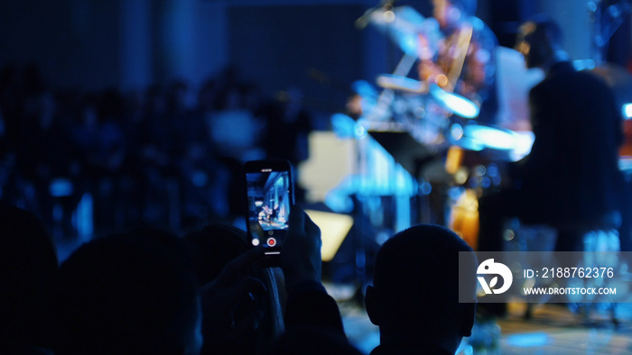 A man recording the jazz performance on his phone