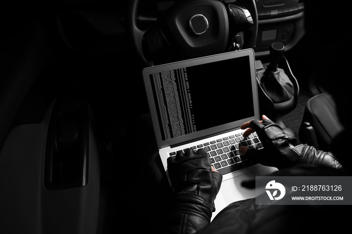 Thief hacking car security system with laptop