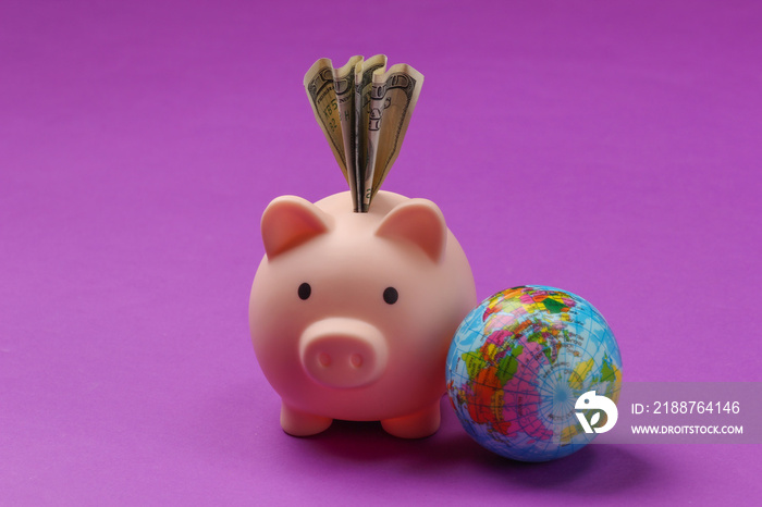 Piggy bank with dollar bill, globe on purple background.