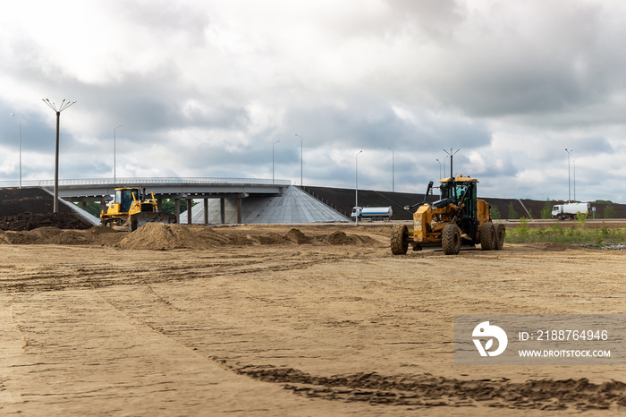 Many heavy heavy industrial road construction machinery on new highway road construction site sunny day with blue sky background. Tipper dumper truck, road-roller and grader machine building freeway