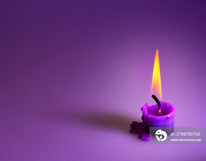 purple candle on a purple background, a bright orange light.