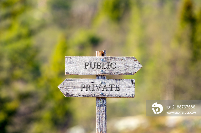 public private text carved on wooden signpost outdoors in nature. Green soft forest bokeh in the background.