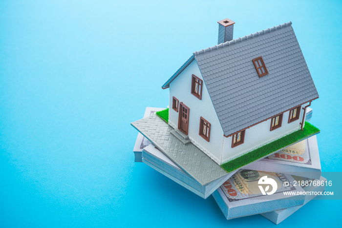 House model, bill dollar banknotes on blue background with copy space. Money saving for new house, home loan, reverse mortgage and real estate property business concept