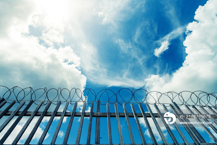 Barbed wire fence surrounding a prison , military or other high security complex.