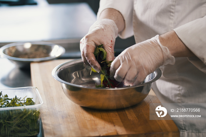 Chef preparing a salad in the kitchen of the restaurant, close up