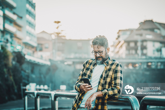 Modern young mature man using phone device outdoor with free internet wifi connection or dat roaming technology. Tourist in the city destination use cellular to plan visits and booking hotel room