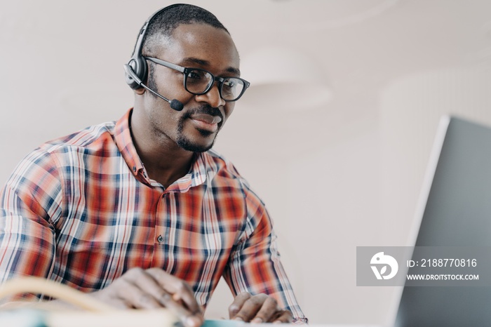 African american male support services worker wearing headset working at laptop. Remote job